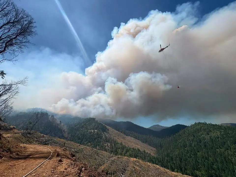 A helicopter flies over the east evans creek fire during suppression efforts last week