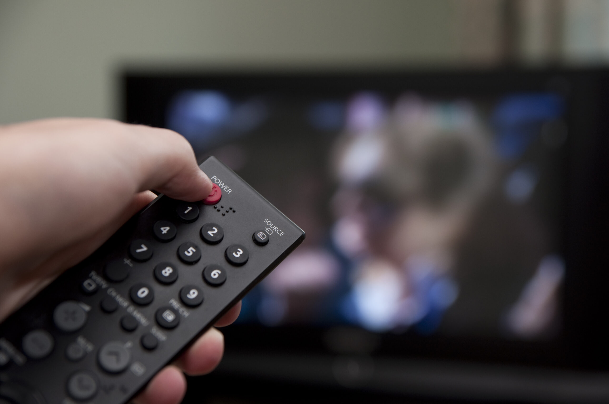 Hand holding tv remote watching campaign ad getty full